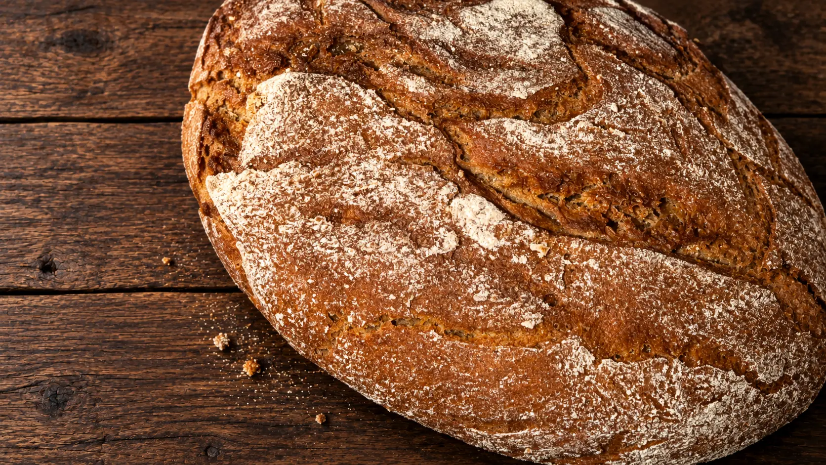 Großer dunkler Brotlaib mit bemehlter, kräftig aufgerissener Kruste